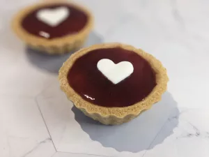 small tart with red filling and a white heart